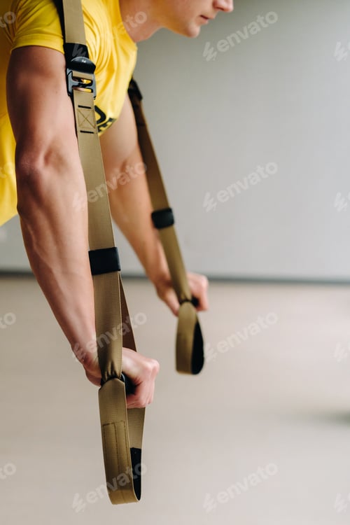 Preview: A focused male athlete performing an exercise on functional loops in the gym
