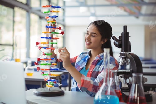 Preview: Attentive schoolgirl experimenting molecule model in laboratory