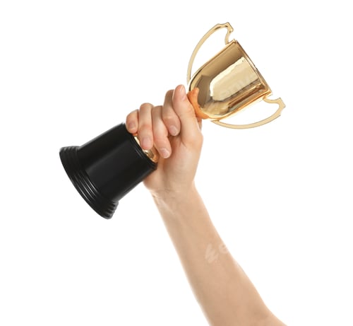 Preview: Young woman holding gold trophy cup on white background, closeup