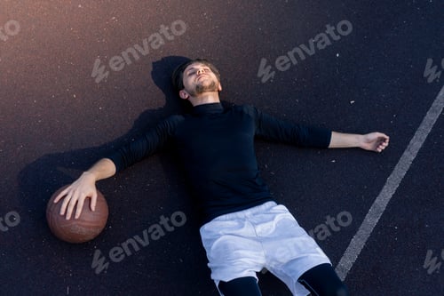 Preview: a sports ground basketball field active recreation guy in white shorts and black t-shirt lies on the