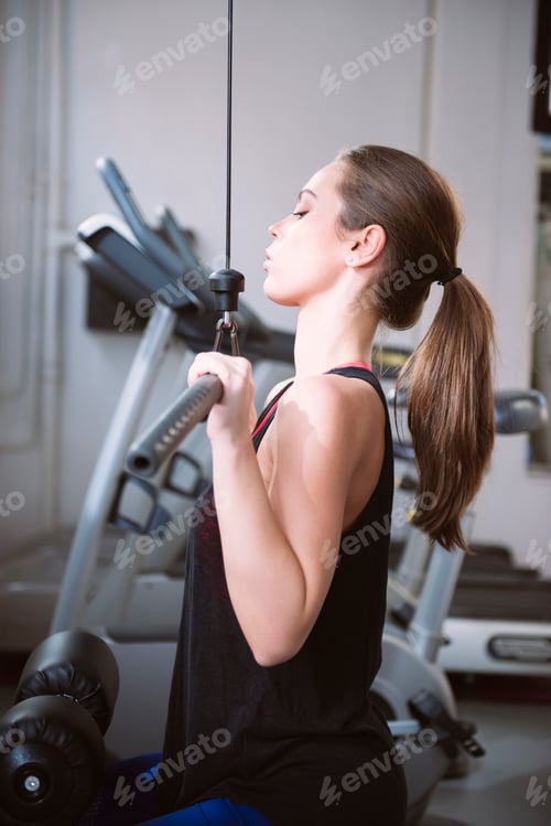 Preview: Young woman doing exercises on a machine at the gym