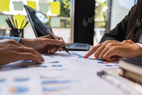 Preview: Two business people sit down to analyze financial data from earnings graphs showing the company's ea