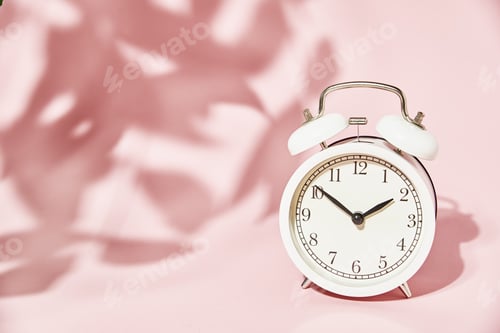 Preview: White alarm clock and leaves shadows on pastel pink background
