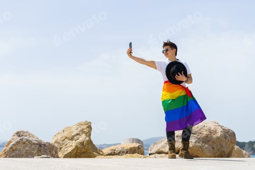 Preview: Woman with LGBT flag tied around her waist taking a photo with a phone