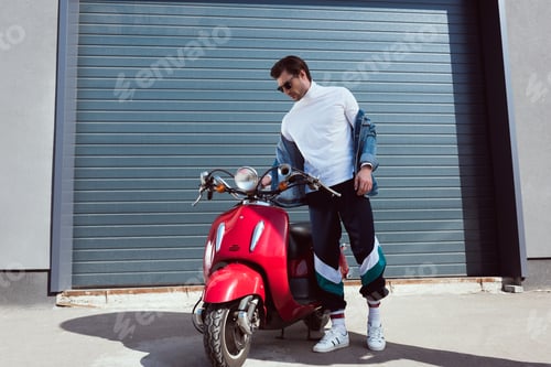 Preview: handsome young man in vintage clothing with red scooter