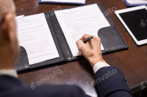 Preview: Hand of businessman with pen putting his signature on document