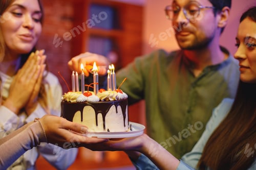 Preview: Friends standing together, holding a plate with a cake and celebrating birthday