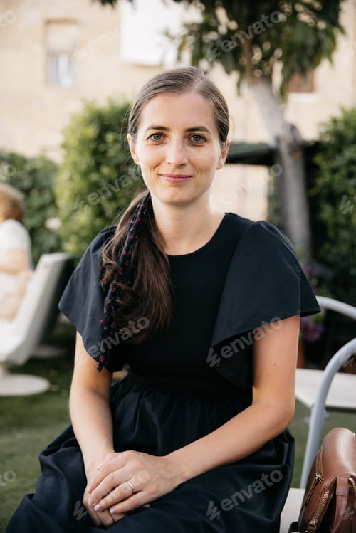Preview: Young woman sitting and smiling in a garden in tuscany