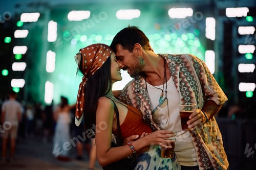 Preview: Happy couple in love in front of music stage during summer festival at night.