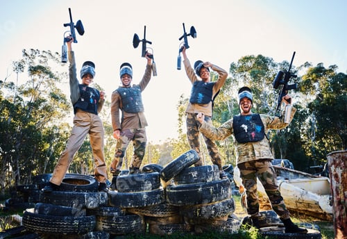 Preview: Team, paintball and portrait in celebration for winning, victory or achievement standing on tires t