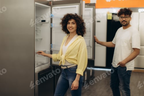 Preview: Couple Examining Refrigerators in Electronics Store for Modern Kitchen Appliance Selection