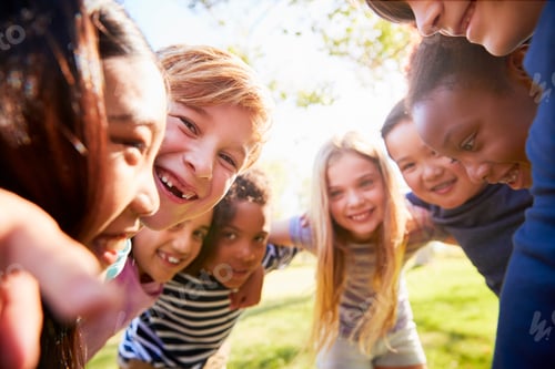 Preview: Group of smiling schoolchildren lean in to camera embracing