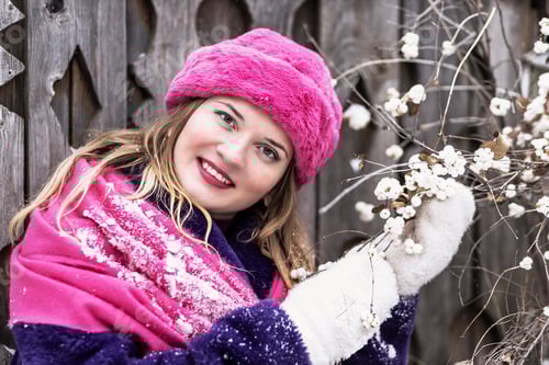 Vorschau: Porträt einer jungen Frau mit Schal und Hut, Fäustlingen und Pelzmantel im Freien in einer Stadt im Winter