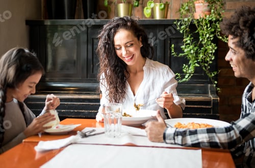 Preview: Happy african american family eating lunch together at restaurant and having fun