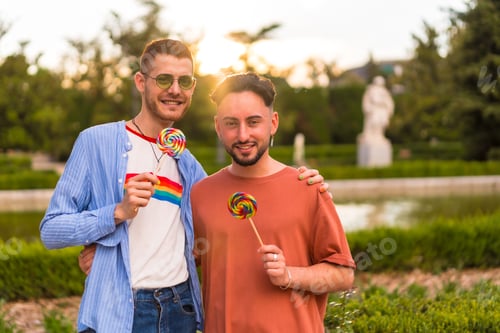 Preview: Portrait of gay boyfriend and girlfriend eating a lollipop in the park on sunset in the city
