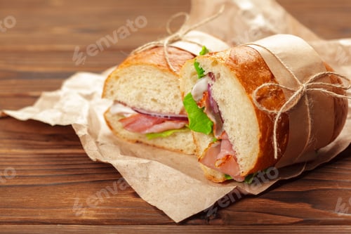 Preview: Fresh sandwich with layers of ham, lettuce, and onion on wooden table during lunchtime