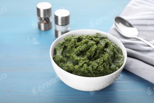 Preview: Bowl with green tasty puree on light blue wooden table