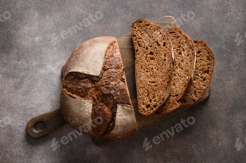 Preview: Loaf of freshly baked sourdough bread with hemp flour on cutting board. Artisan bread with seeds.