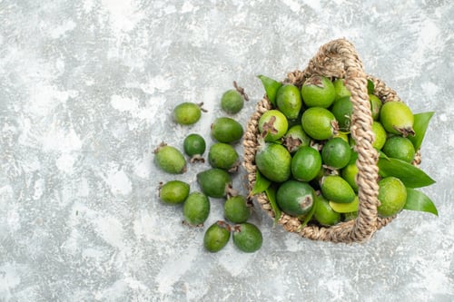 Preview: top view fresh feijoas in wicker basket on grey isolated background free space