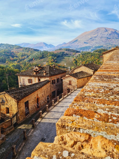Preview: Cityscape of Montefortino with beautiful Sibillini mountains in the background under a cloudy sky