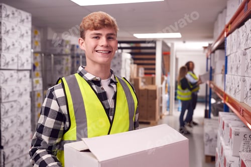 Preview: Portrait Of Male Worker Inside Busy Warehouse Carrying Box