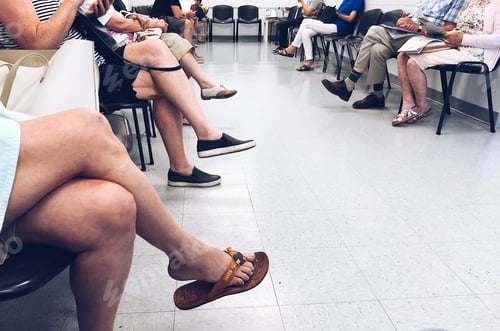Preview: People sitting on chairs waiting their turn in a waiting room at a doctors office