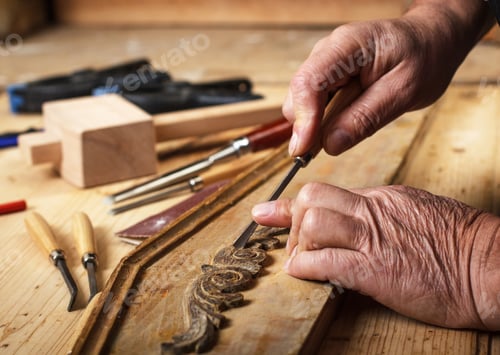 Preview: Close up of senior carpenter working with a hammer, chisel and wood carving tools.