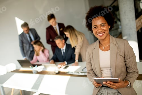 Preview: African American businesswoman standing and using digital tablet in a modern office