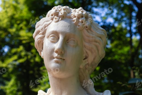 Preview: Close-up of sculpture woman's head of white marble in summer park, shallow DOF. Decorative garden