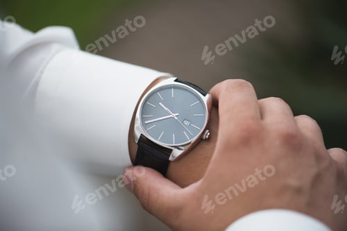 Preview: Close up of businessman looking at watch on his hand outdoors, free space.