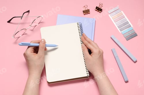 Preview: Woman with planner and stationery on pink background, top view