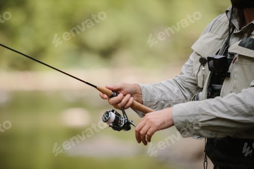 Preview: Fisherman holding fishing rod, enjoying trout fishing in nature