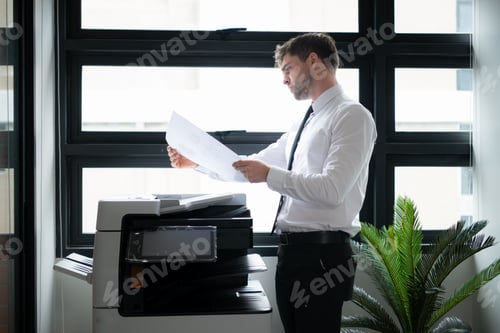 Preview: Businessman in office working with copier.