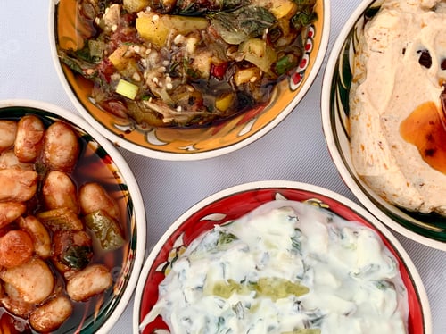 Preview: Turkish meze or appetizers in a small ceramic plates on a white table cloth. Colorful food