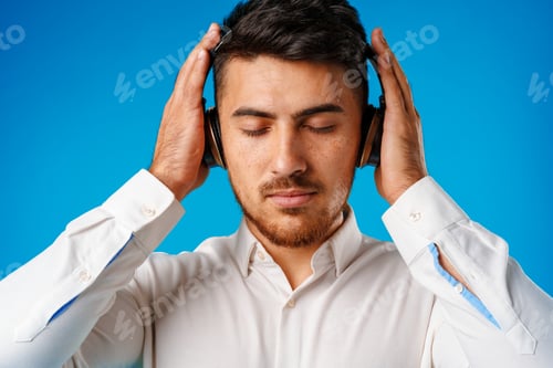 Preview: Handsome young mixed-race man listening to music with blue headphones