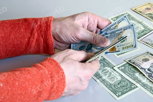 Preview: Caucasian man's hands counting dollar banknotes on gray surface.