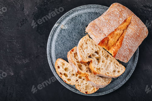 Preview: Italian ciabatta bread slices with on stone plate on dark concrete background