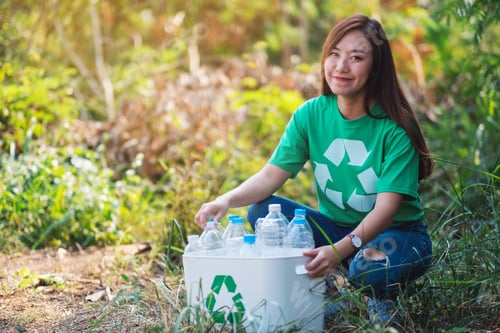 Preview: An asian woman collecting garbage plastic bottles into a recycle bin in the outdoors
