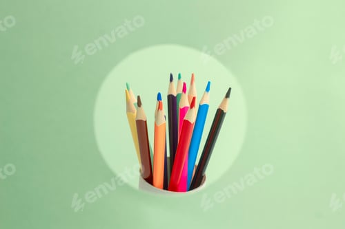 Preview: A set of colored pencils peek out of a pink circle on a green background. Sharpened pencils concept