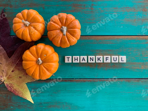 Preview: Fall Flat Lay with pumpkins & leaves on green wooden background & word Thankful with tiles