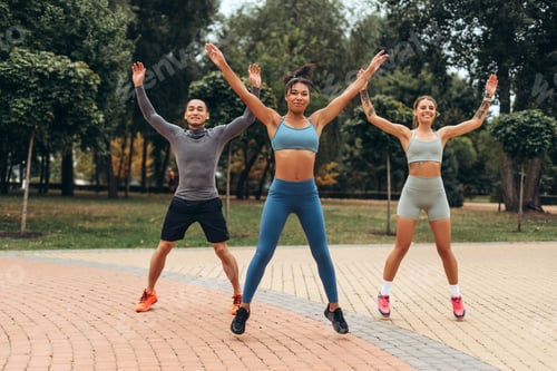 Preview: Group of happy, attractive, multinational people wearing stylish sportwear jumping, doing exercises