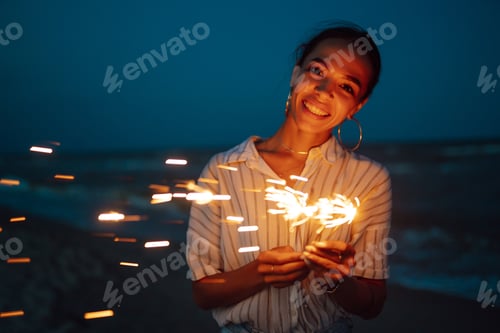 Preview: Glowing sparkles in hands. Women with Christmas sparklers on nature and twillight sky background.