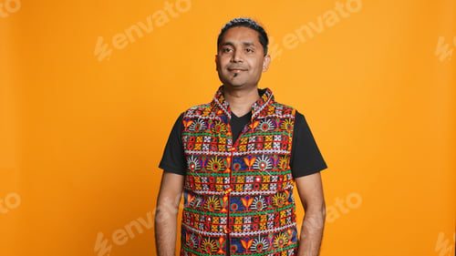 Preview: Portrait of optimistic man wearing colorful vest, studio backdrop