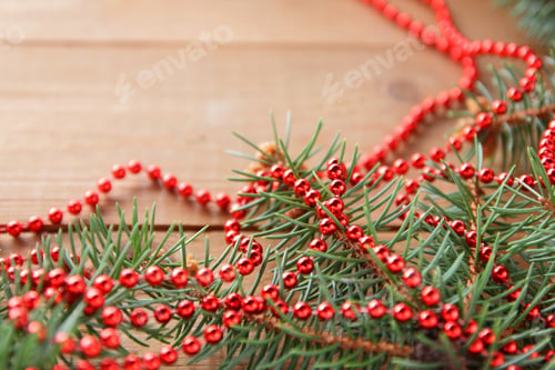 Preview: Fir Branches And Red Necklace On Wooden Boards. Christmas Decorations On Wooden Background