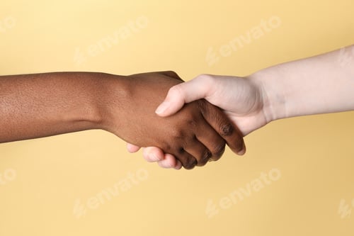 Preview: Stop racism. People of different skin colors shaking hands on beige background, closeup
