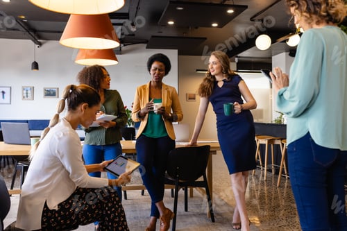 Preview: Diverse female colleagues in discussion using tablet in casual meeting in office