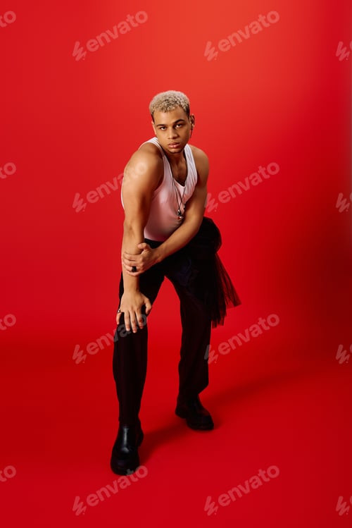 Preview: Stylish young man poses confidently in vibrant red studio setting with flair