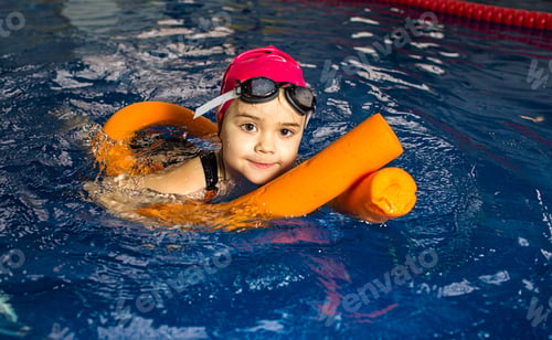 Preview: Young girl practices swimming using flotation aids in a bright indoor pool during afternoon