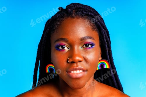 Preview: Female with rainbow make-up and long eyelashes in blue studio baclground