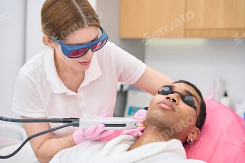 Preview: Professional cosmetician carrying out hair removal procedure on male client